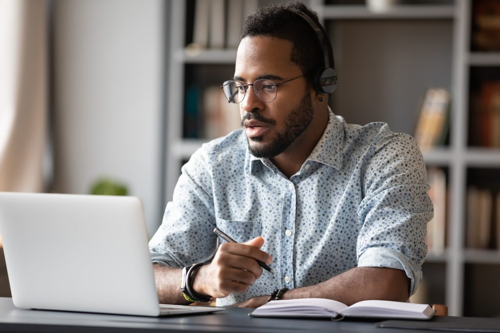 Focused,Young,African,Businessman,Wear,Headphones,Study,Online,Watching,Webinar